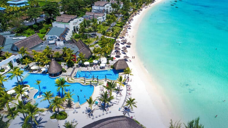 Luxurious beachfront resort at Ambre Mauritius with pools, palm trees, and white sandy beach for a perfect holiday experience.