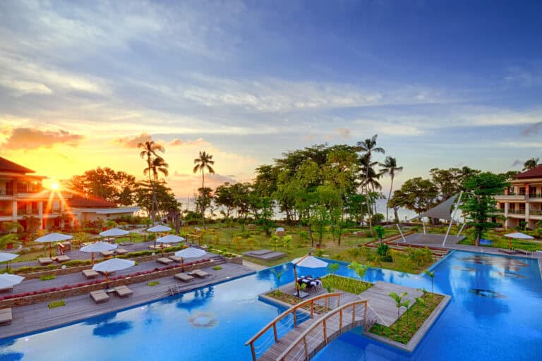 Scenic view of Savoy Seychelles Resort & Spa pool at sunset with lush greenery.