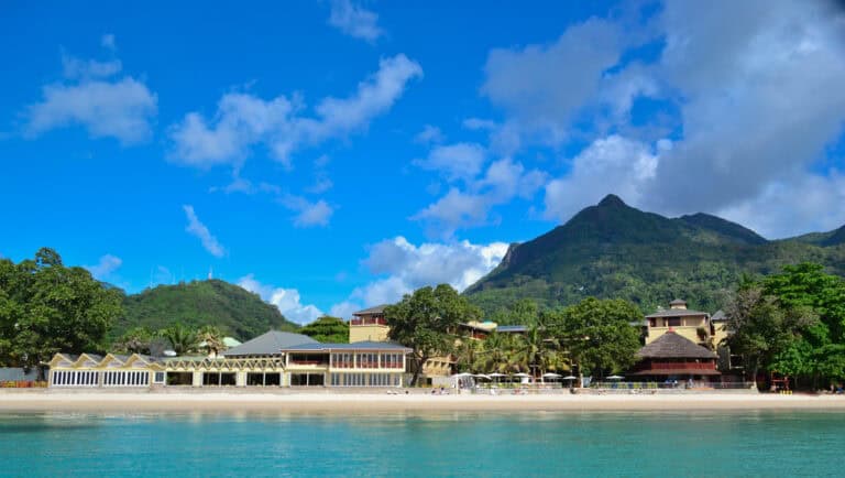 Beautiful beach view with mountains and resort buildings in the background.