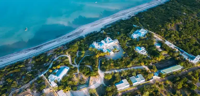 Aerial view of a coastal resort with lush greenery and modern buildings near the beach.
