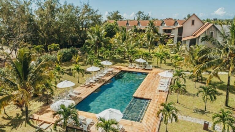 Swimming pool at Crystals Beach Resort with palm trees and sun umbrellas.