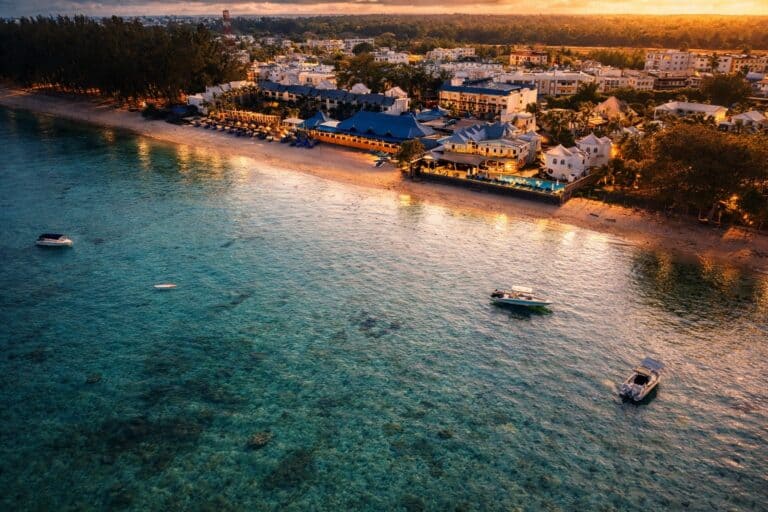 Pearle Beach Resort and Spa on the coast with boats in clear waters.