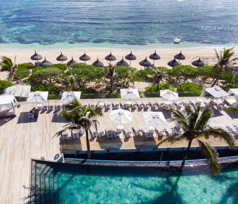 Beach resort with umbrellas, lounge chairs, and pool at Radisson Blu Poste Lafayette.
