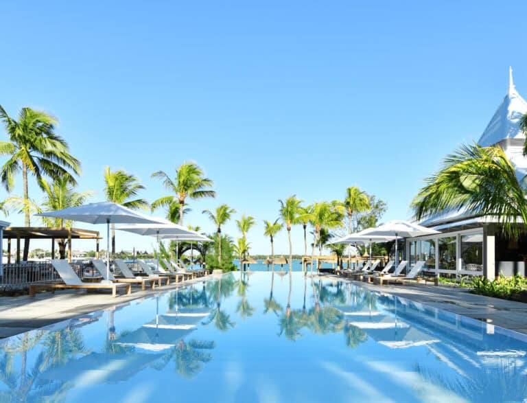 Luxury pool at Veranda Grand Baie Hotel with palm trees and clear blue sky.