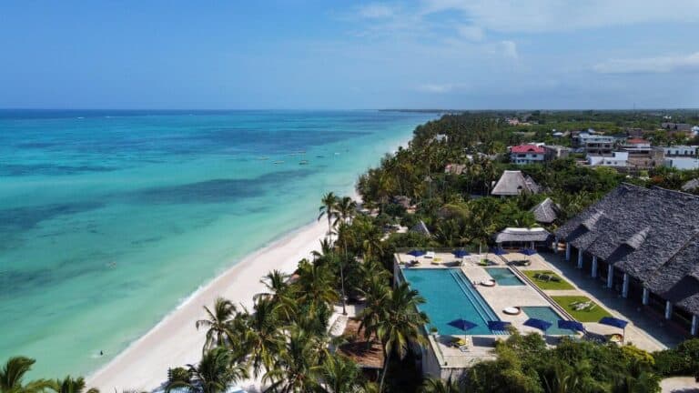Aerial view of a tropical beach resort with turquoise waters and lush greenery.