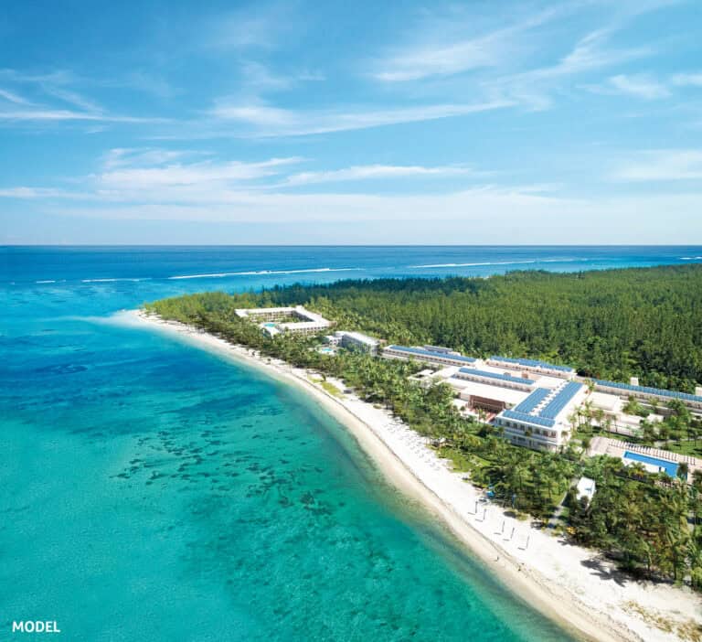Aerial view of Riu Palace Mauritius beachfront resort with lush greenery and turquoise ocean.