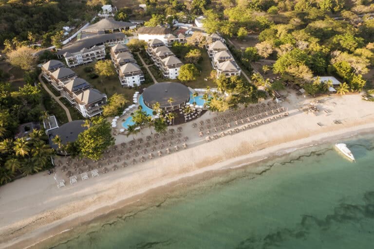 Beachfront view of Royal Andilana Resort and Spa with pool and sun loungers.