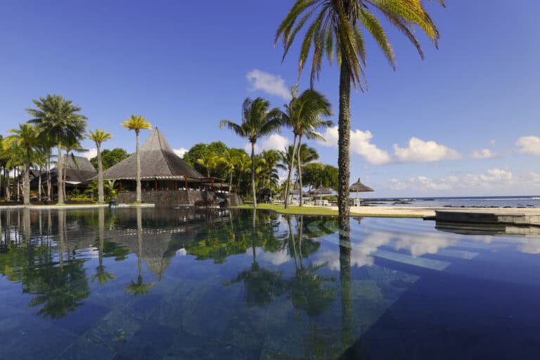 Luxury resort pool with palm trees and ocean view at Shanti Maurice Resort & Spa.