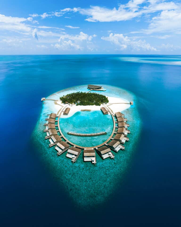 Aerial view of Kudadoo Maldives Private Island with overwater bungalows and lush greenery.