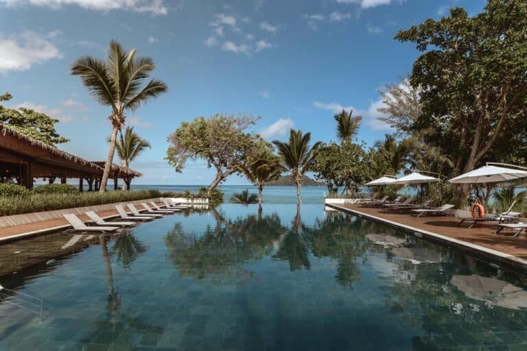 Luxury hotel pool with palm trees and ocean view in Nosy Be.