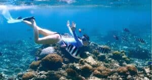 Woman snorkeling over vibrant coral reef with tropical fish in Mauritius.