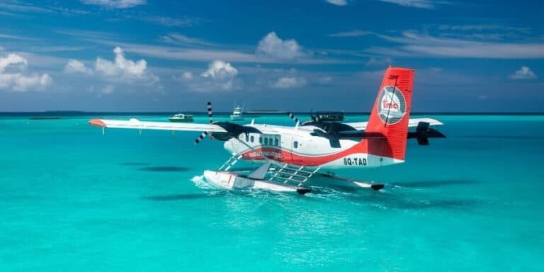 Seaplane flying over turquoise ocean in Maldives for transfer services.