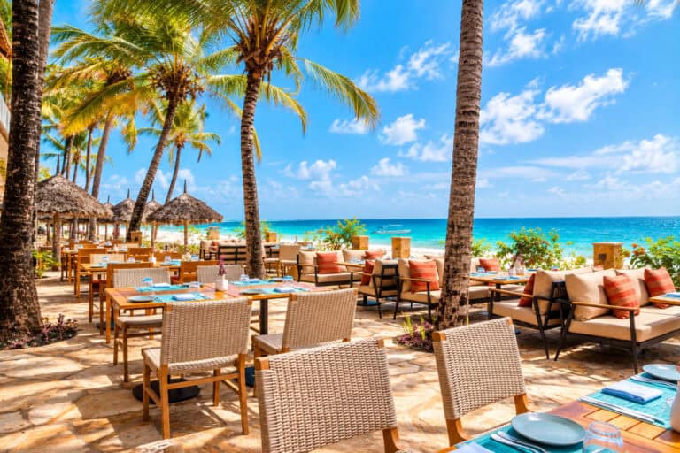 Beachside dining area with palm trees and ocean view at JAZ Elite Adonia.